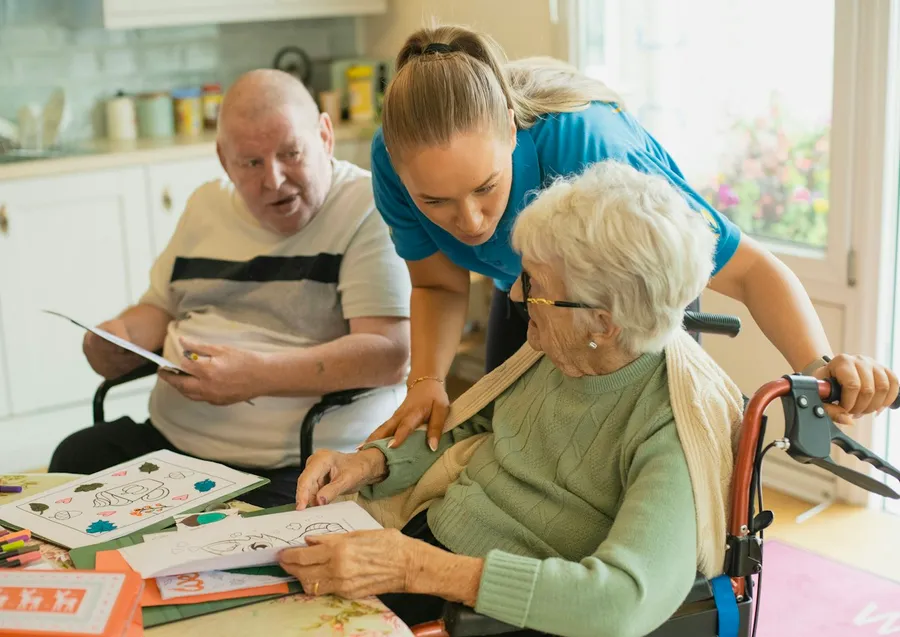 A caregiver helping an older woman with an activity at home